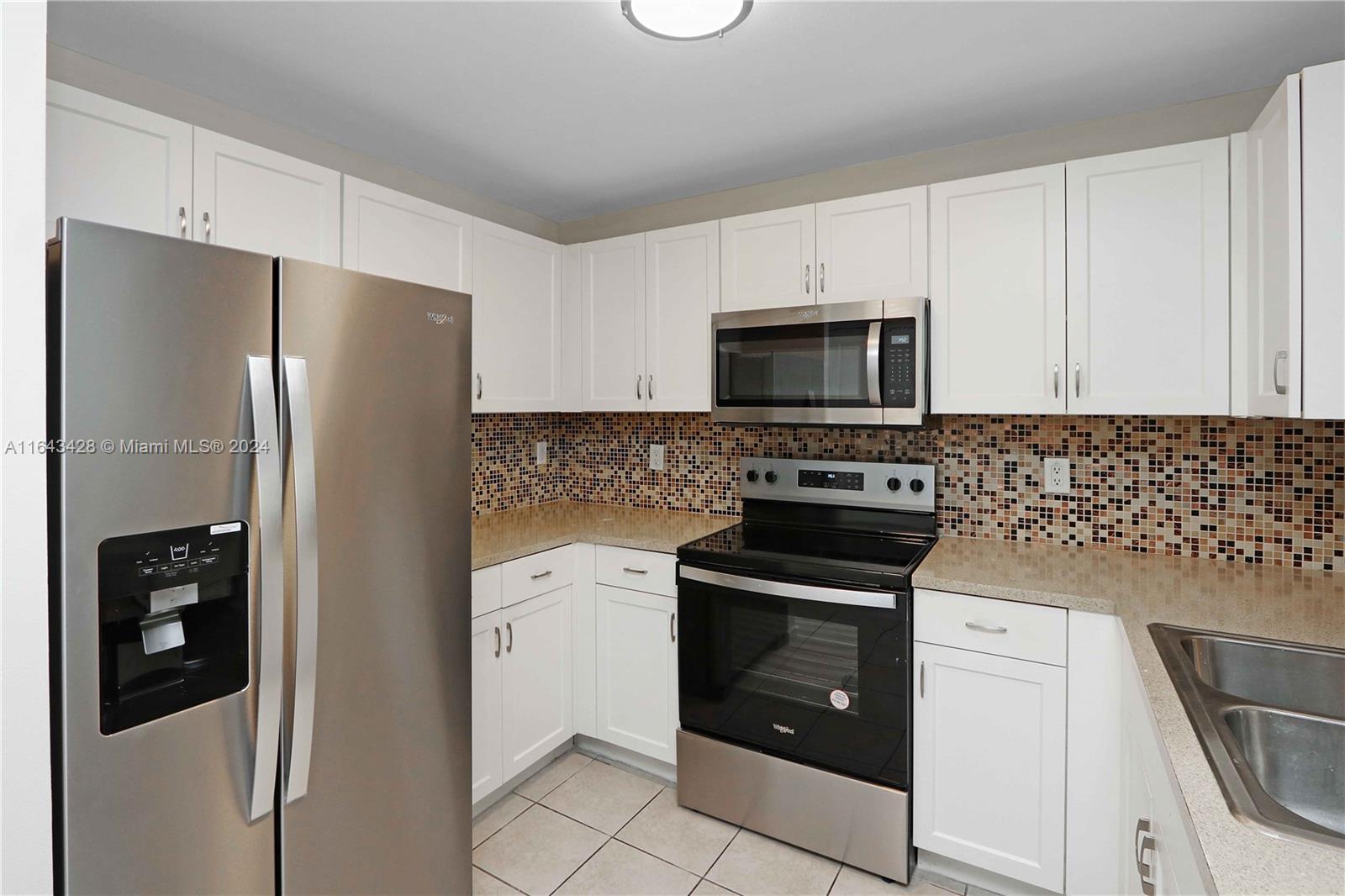 a kitchen with a refrigerator stove and white cabinets