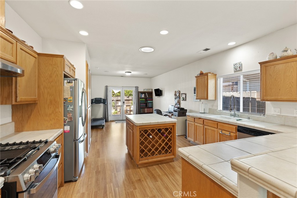 a large kitchen with stainless steel appliances granite countertop a stove refrigerator and a view of living room