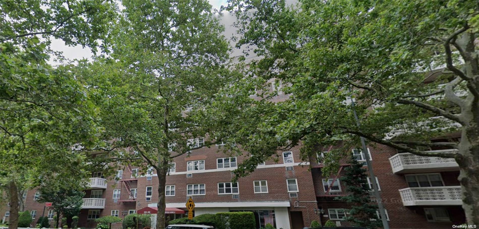 a front view of a residential apartment building with a tree in front