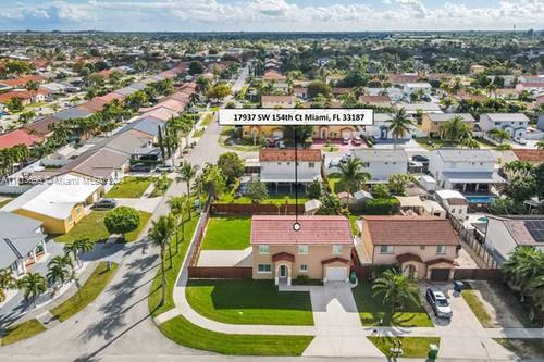 an aerial view of residential houses with outdoor space and parking