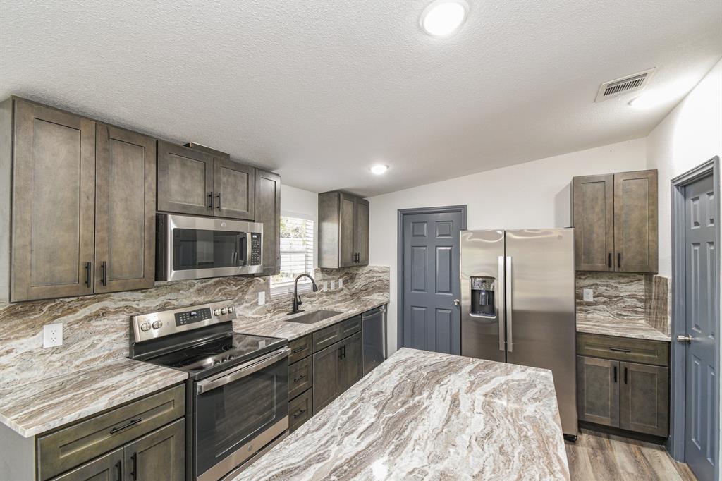 a kitchen with refrigerator a microwave a stove and cabinets