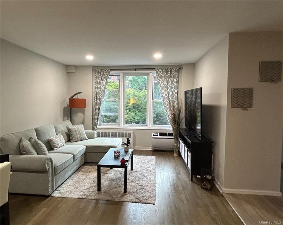 Living room with dark hardwood / wood-style floors and radiator