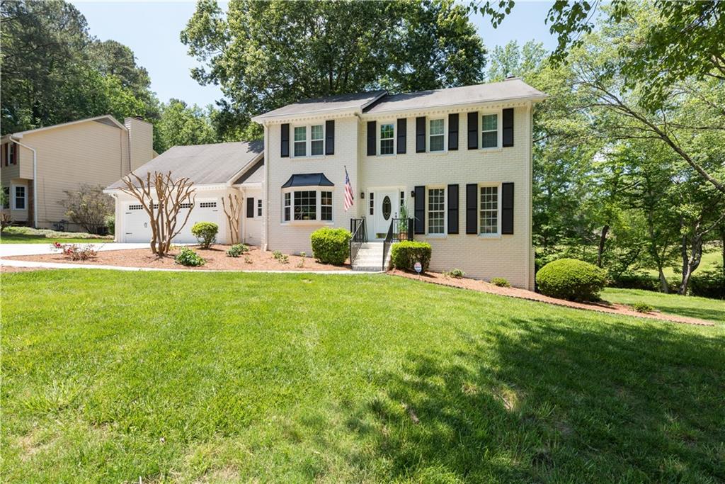 a front view of a house with a yard and trees