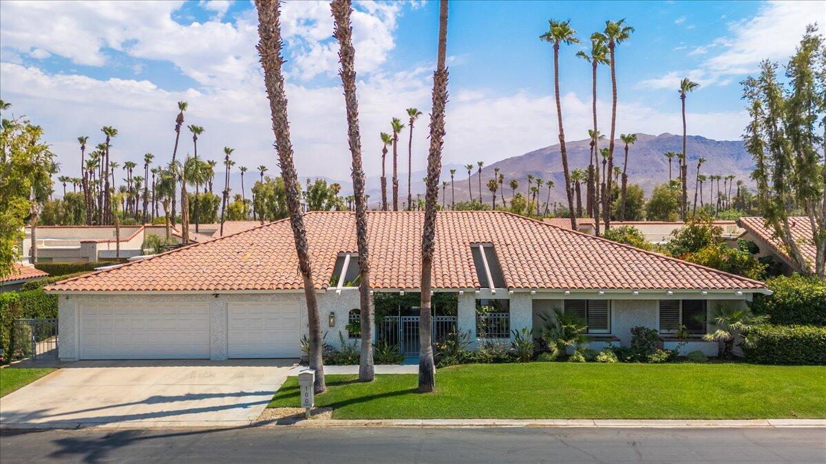 a view of a white house with a yard and palm trees