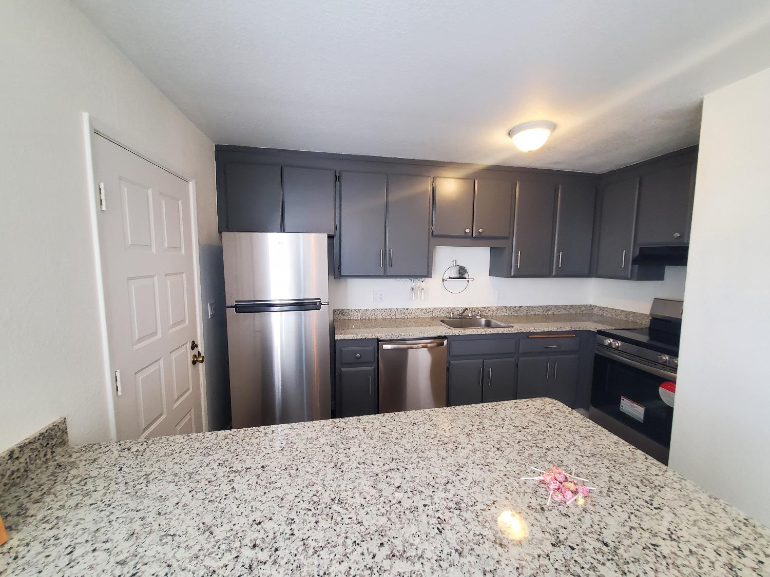 a kitchen with granite countertop a refrigerator stove top oven and sink