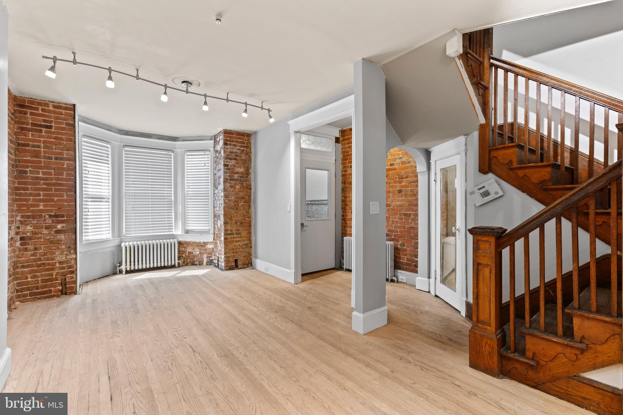 a view of an empty room with wooden floor and fan