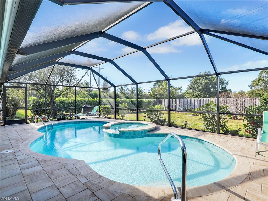 a swimming pool with lawn chairs under an umbrella