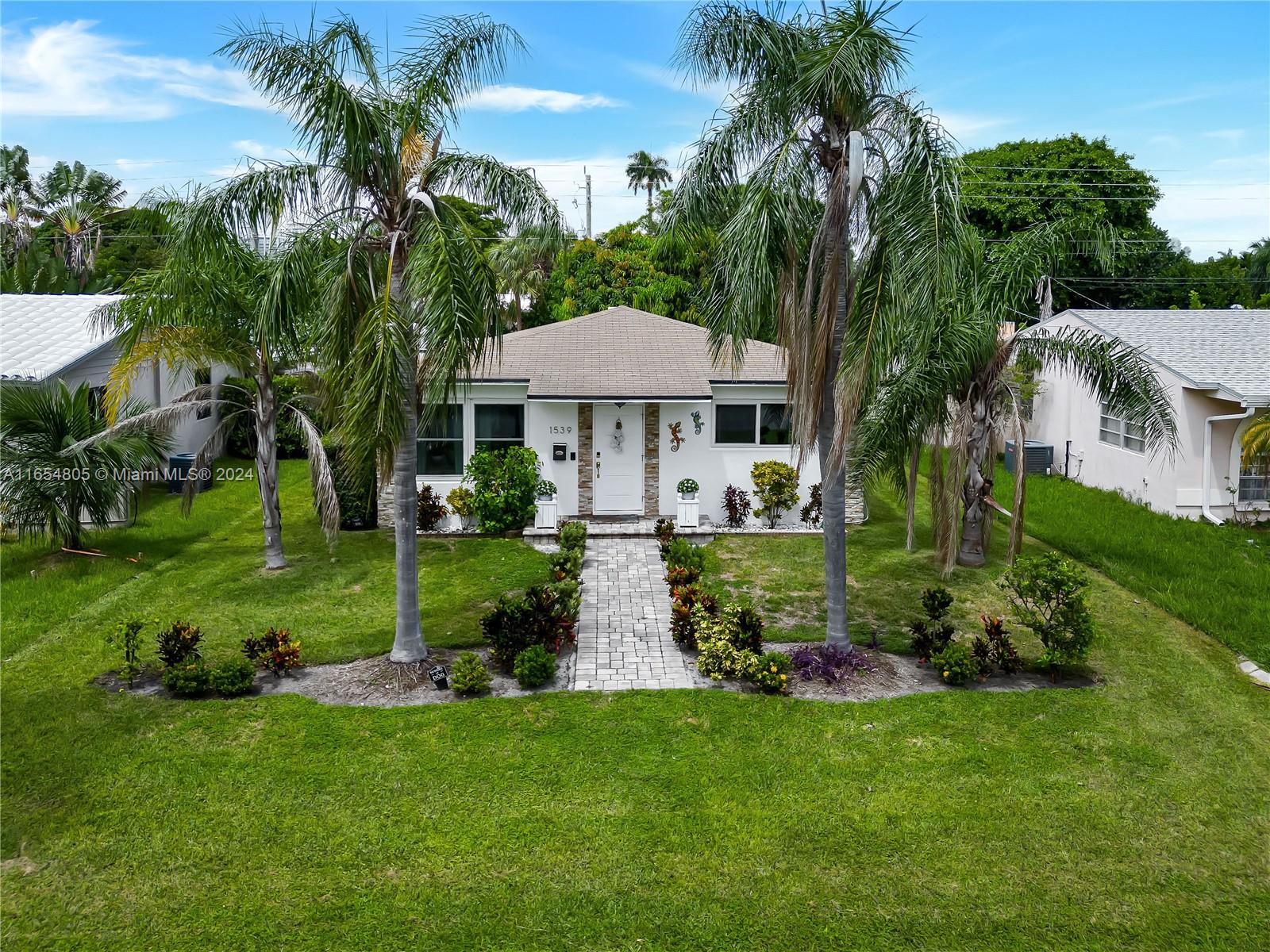 a front view of a house with a yard and potted plants