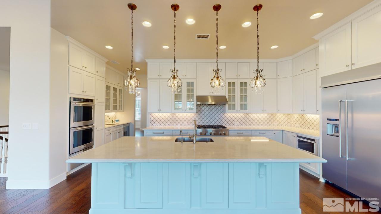 a kitchen with kitchen island a large counter top stainless steel appliances and wooden floor