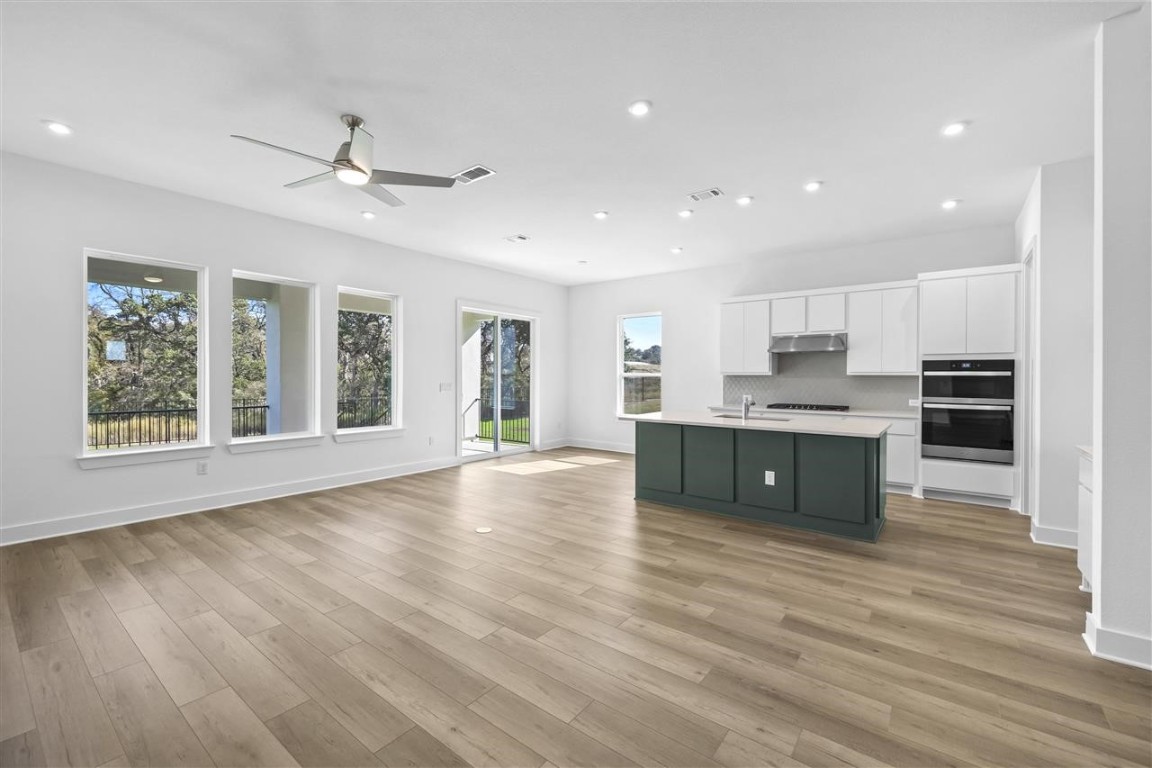 a large kitchen with stainless steel appliances kitchen island a large counter top and a wooden floors