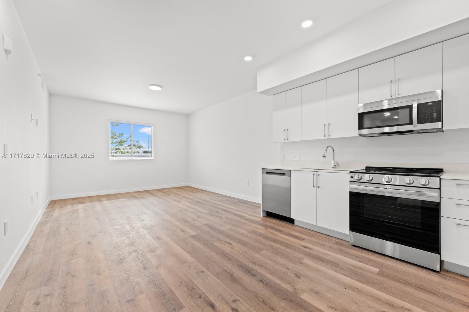 a kitchen with stainless steel appliances granite countertop a stove a microwave and white cabinets