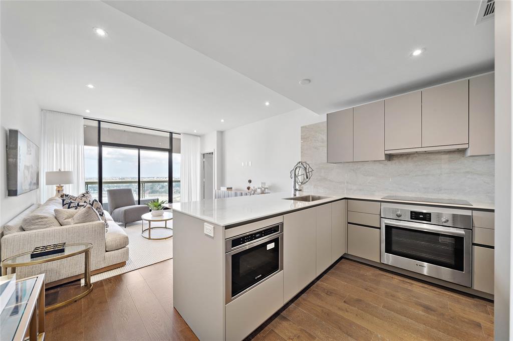 a kitchen with a stove a sink and white cabinets with wooden floor next to windows