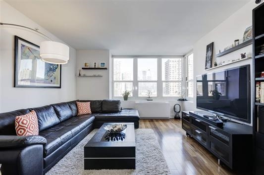 a living room with furniture a flat screen tv and a window