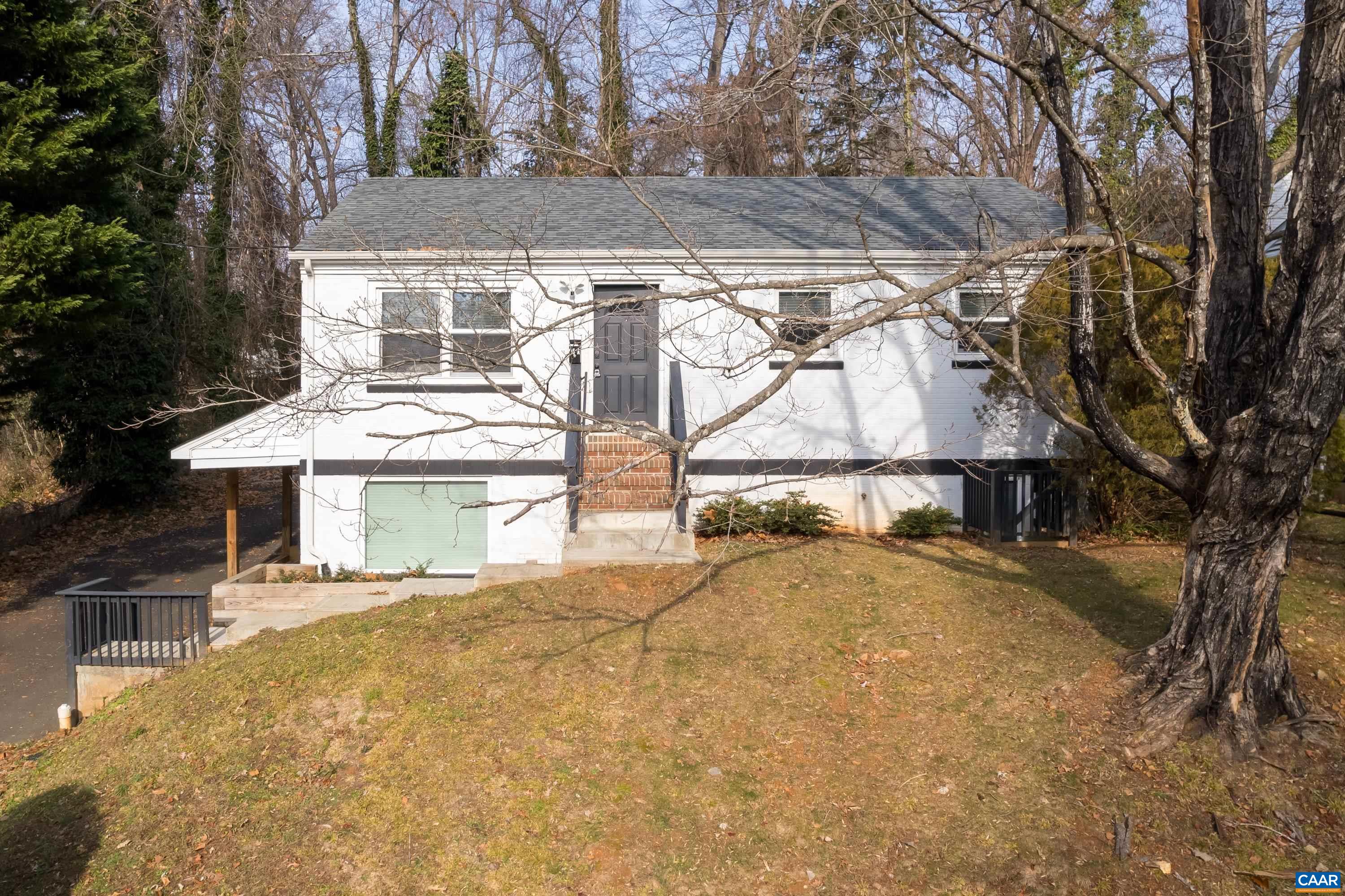 a view of a house with a yard and large trees