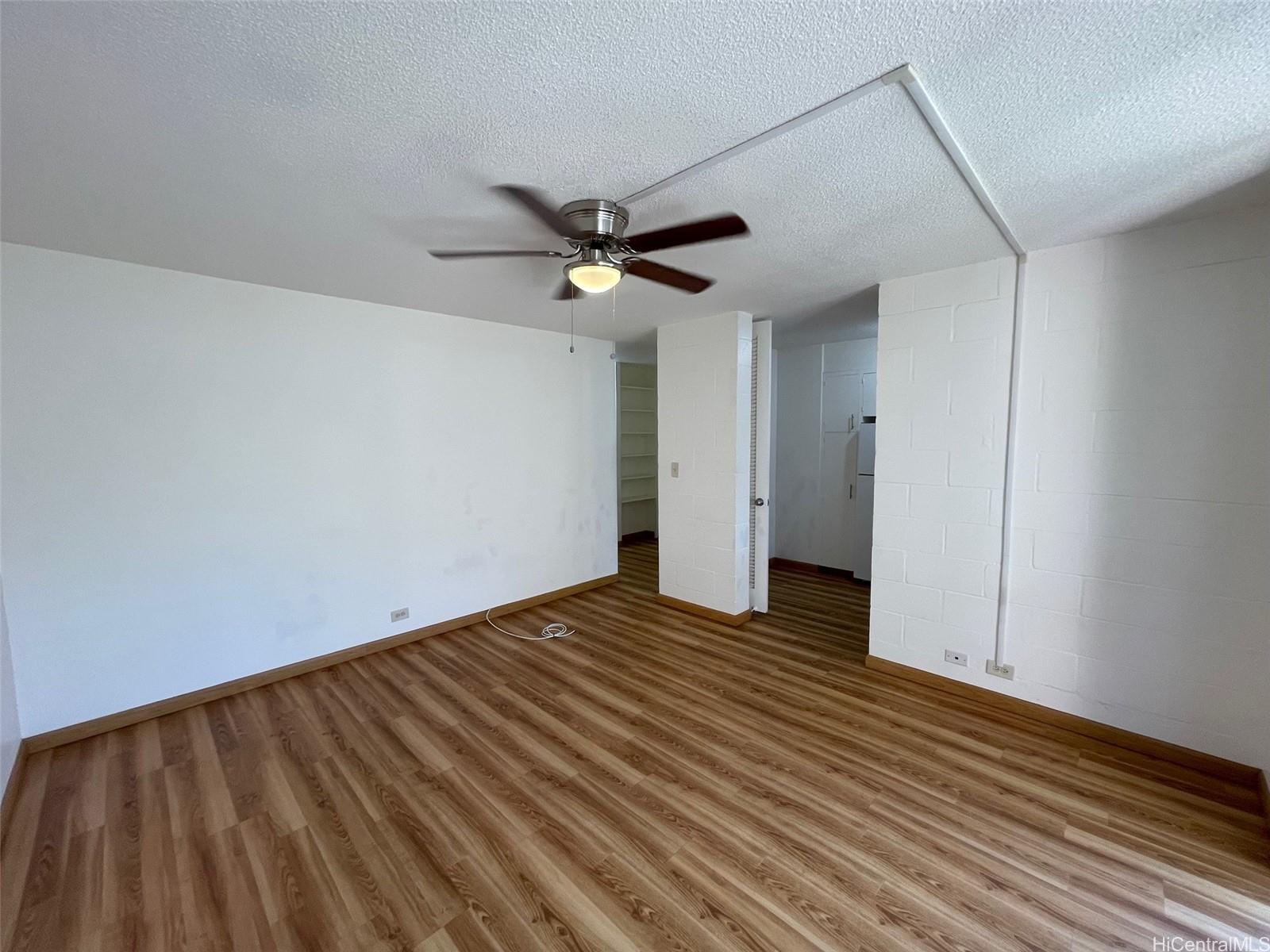 a view of a big room with wooden floor and a ceiling fan