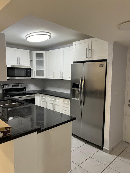 a kitchen with granite countertop a refrigerator and a sink