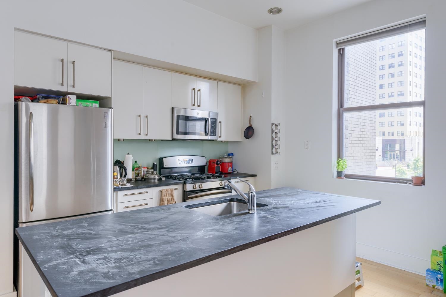 a kitchen with kitchen island a counter top space a sink appliances and cabinets