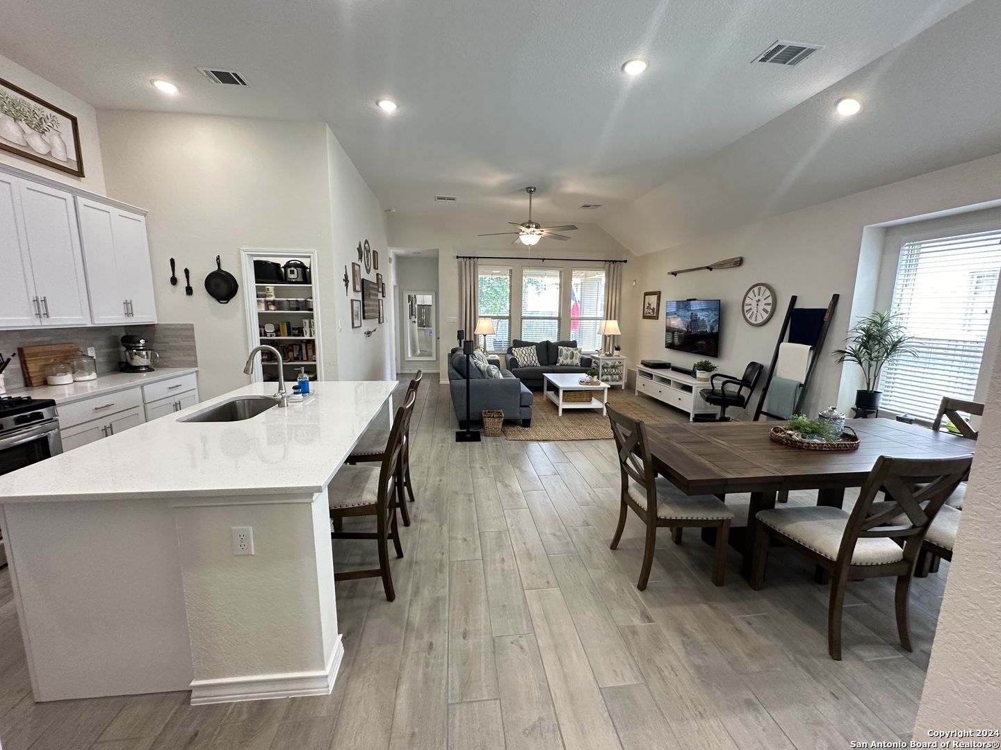 a living room with stainless steel appliances furniture a rug and a kitchen view