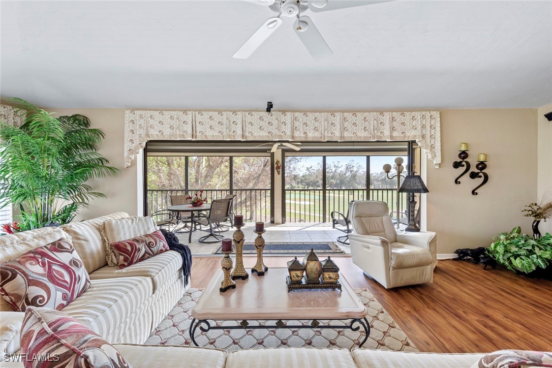 a living room with furniture large windows and wooden floor