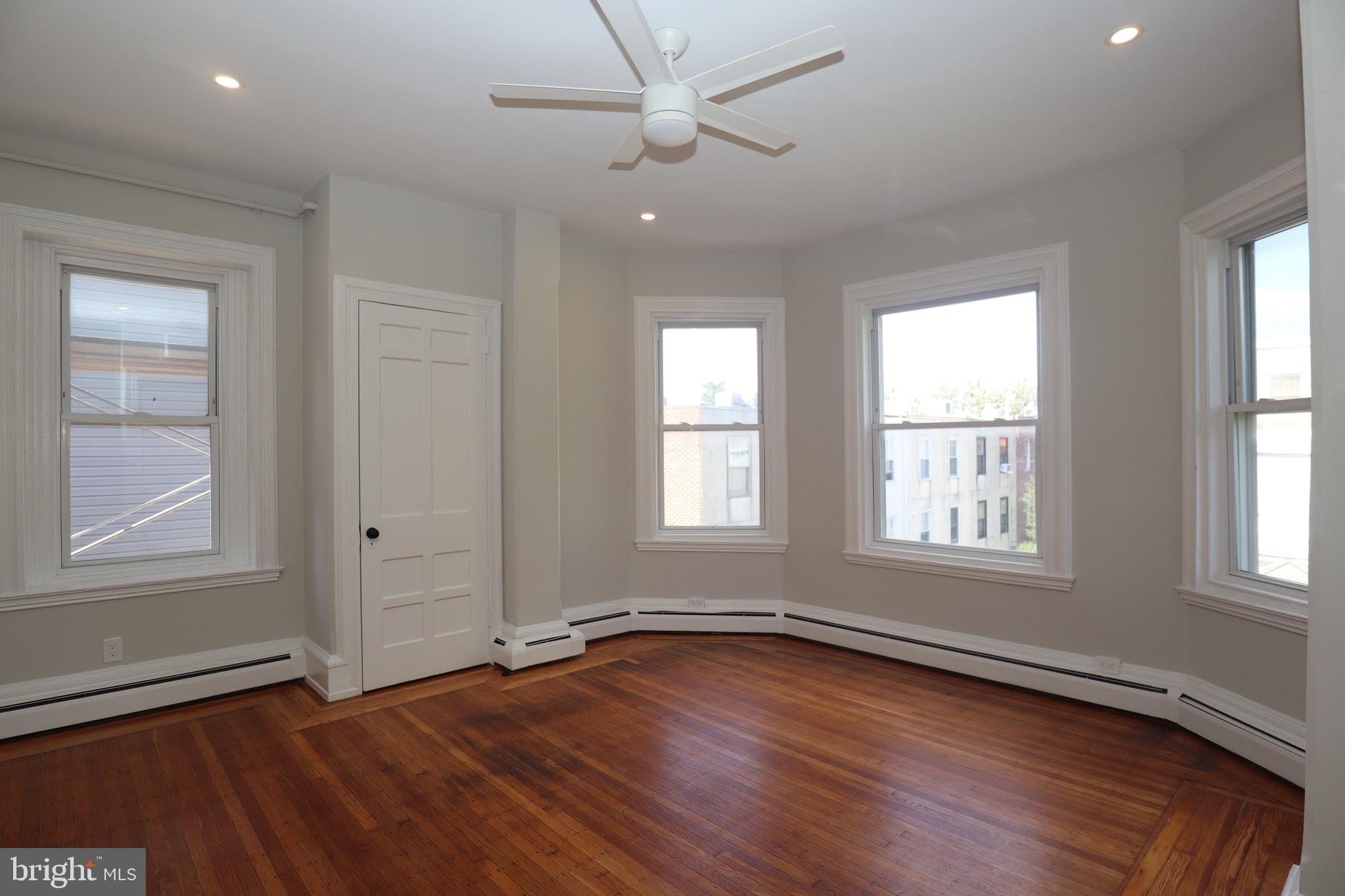 an empty room with wooden floor and windows