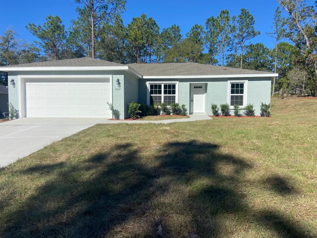 a front view of house with yard and trees in the background