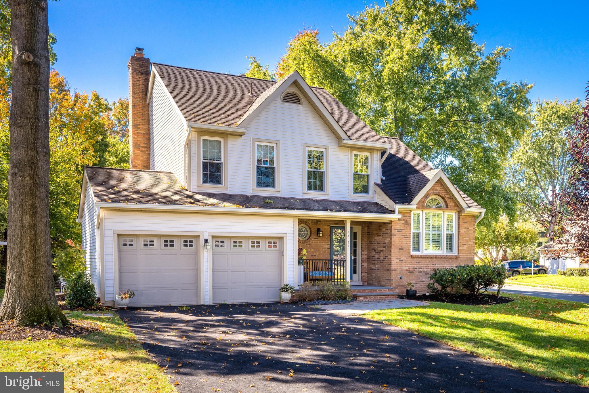 a view of a house with a yard plants and large tree