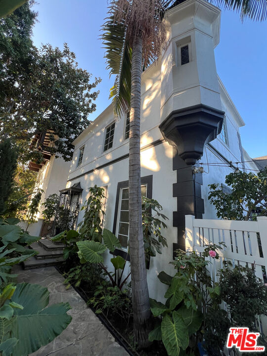 a view of a house with a small yard plants and a large tree