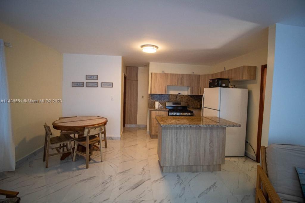 a kitchen with granite countertop a table chairs stove and refrigerator