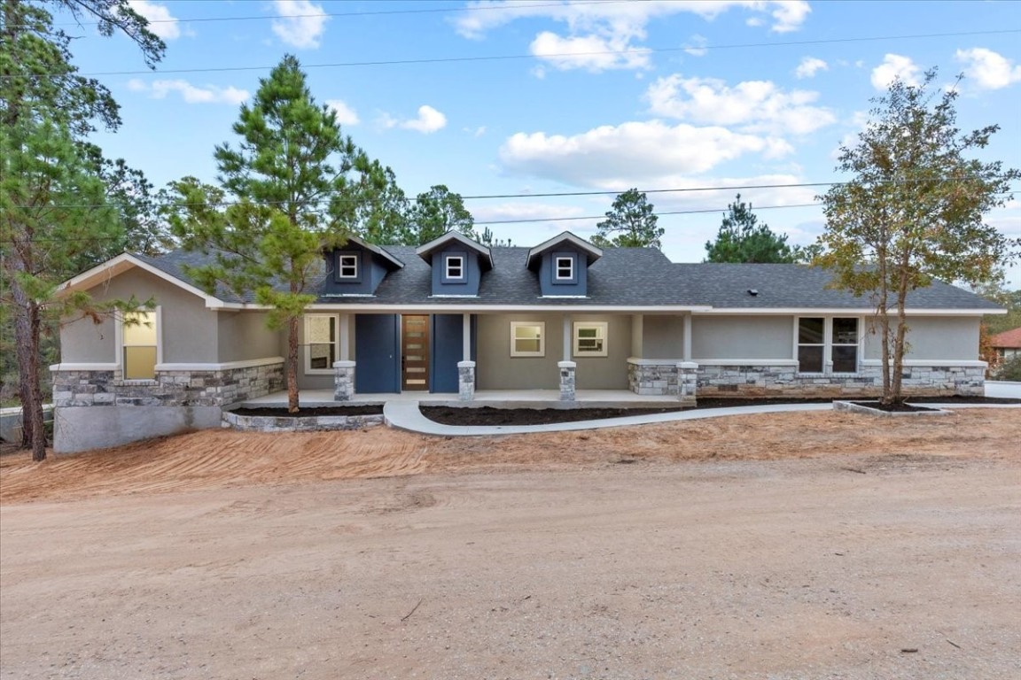 front view of house with a yard and trees in the background