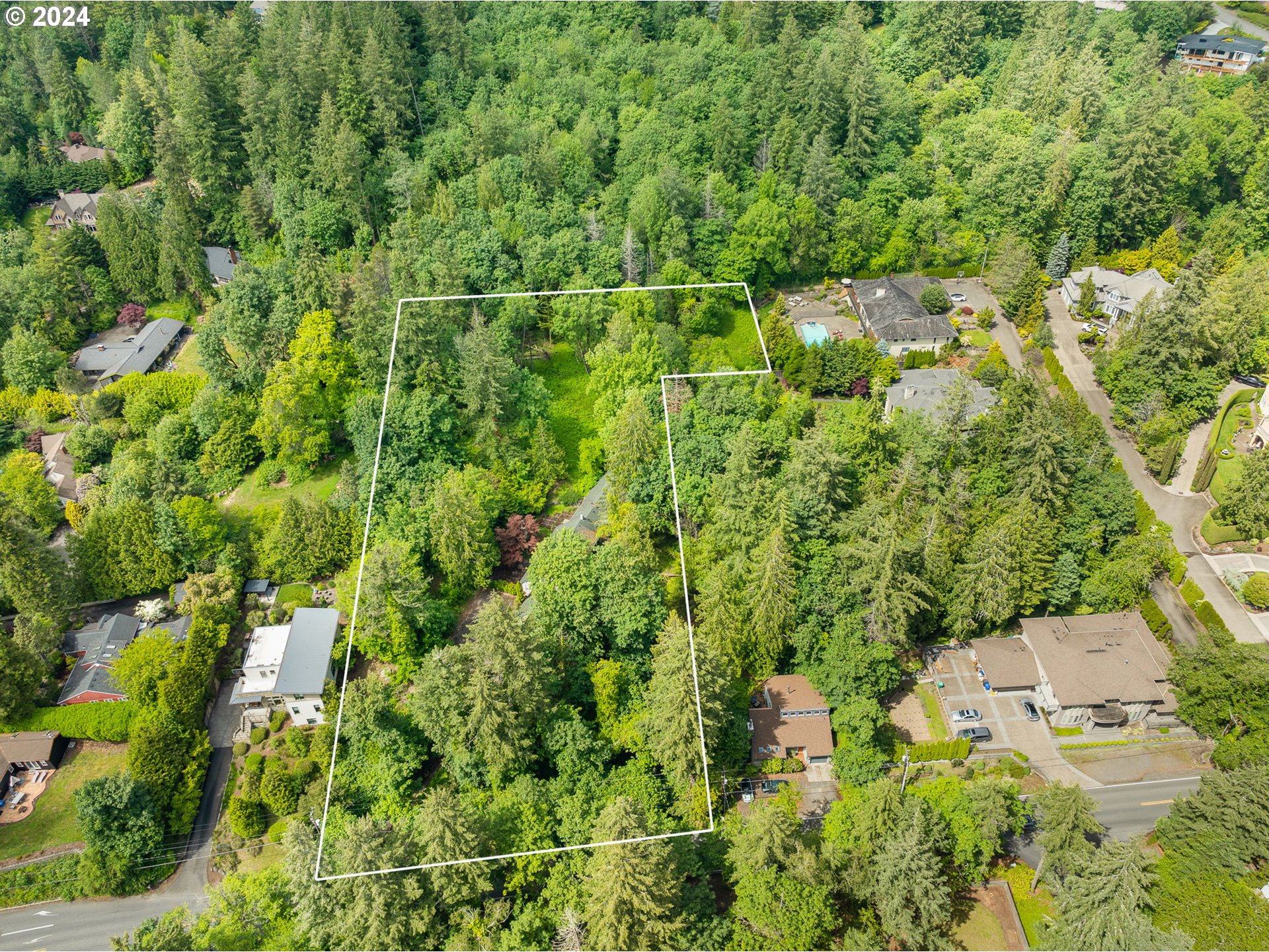 an aerial view of residential house with outdoor space and trees all around