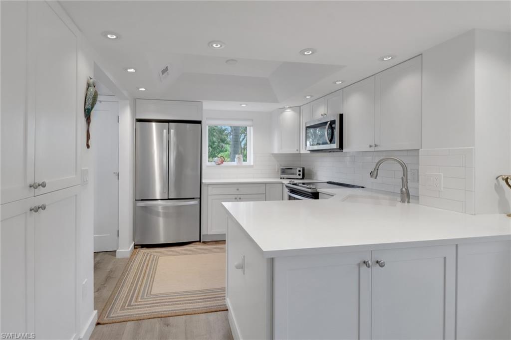 a kitchen with stainless steel appliances a refrigerator sink and white cabinets