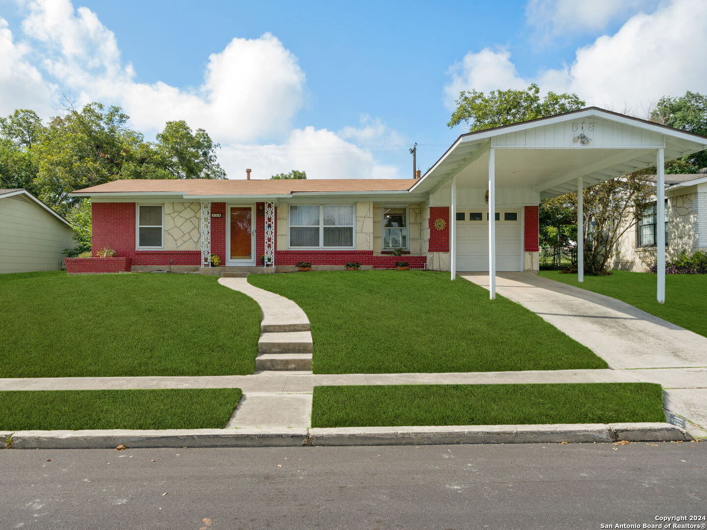 a front view of a house with a garden and trees