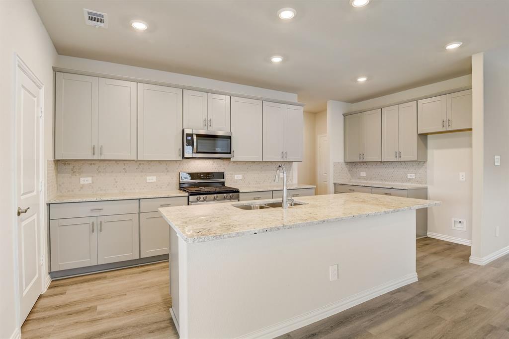 a kitchen with stainless steel appliances granite countertop a sink a stove a refrigerator and cabinets