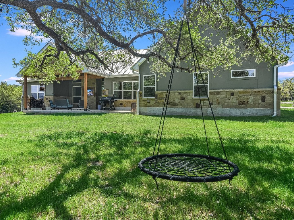 a backyard of a house with plants and large tree