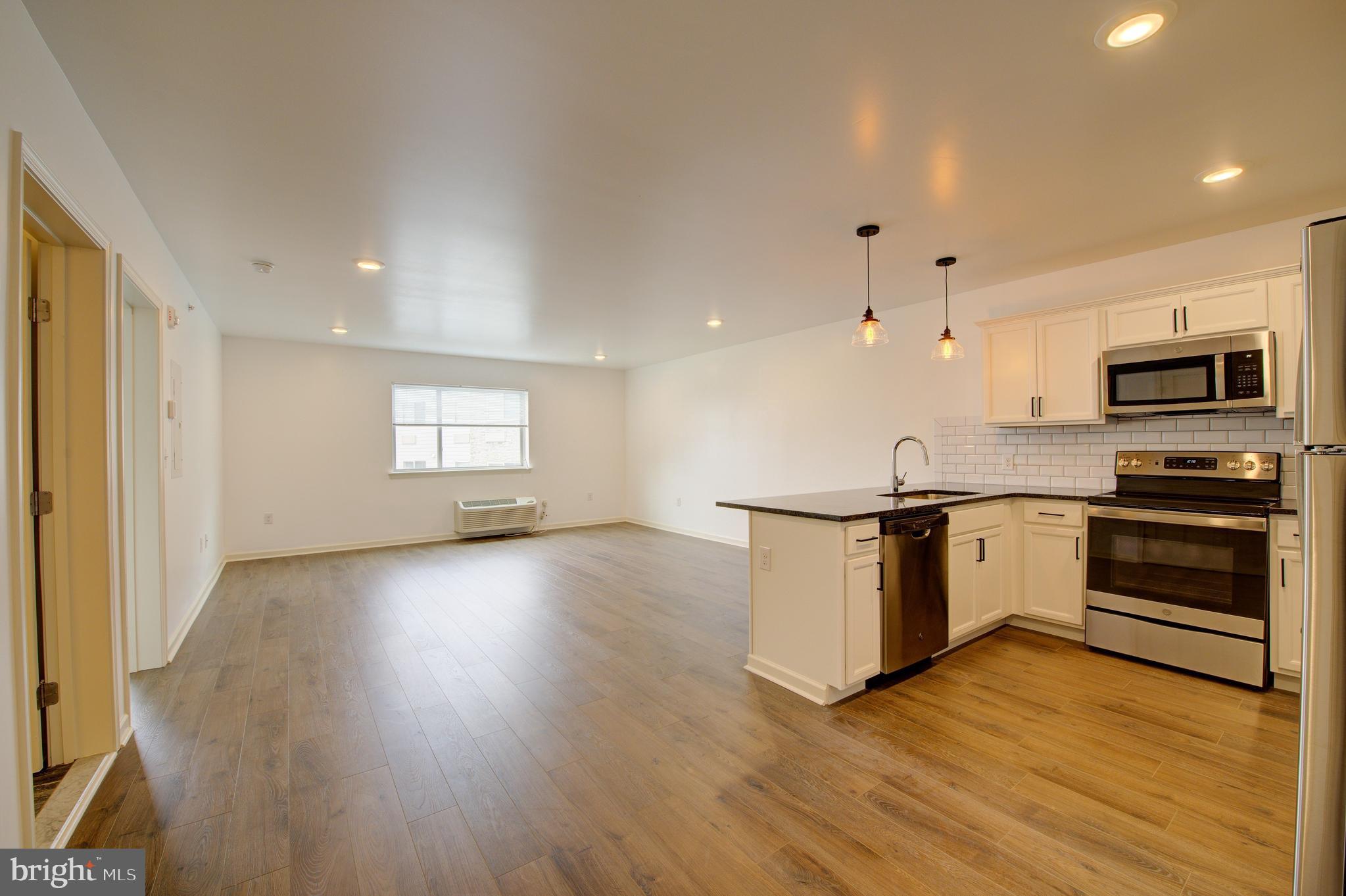 a kitchen with granite countertop a stove a sink and a microwave