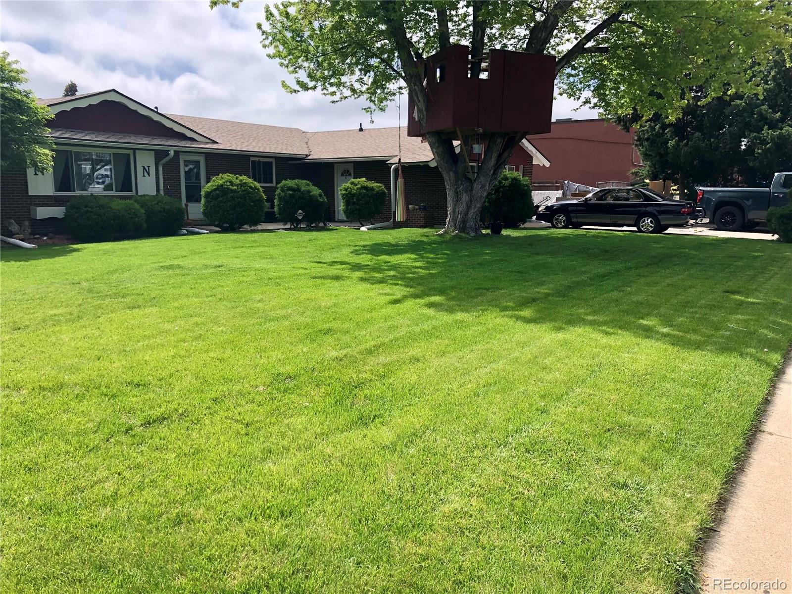 a view of a brick house with a yard and large trees