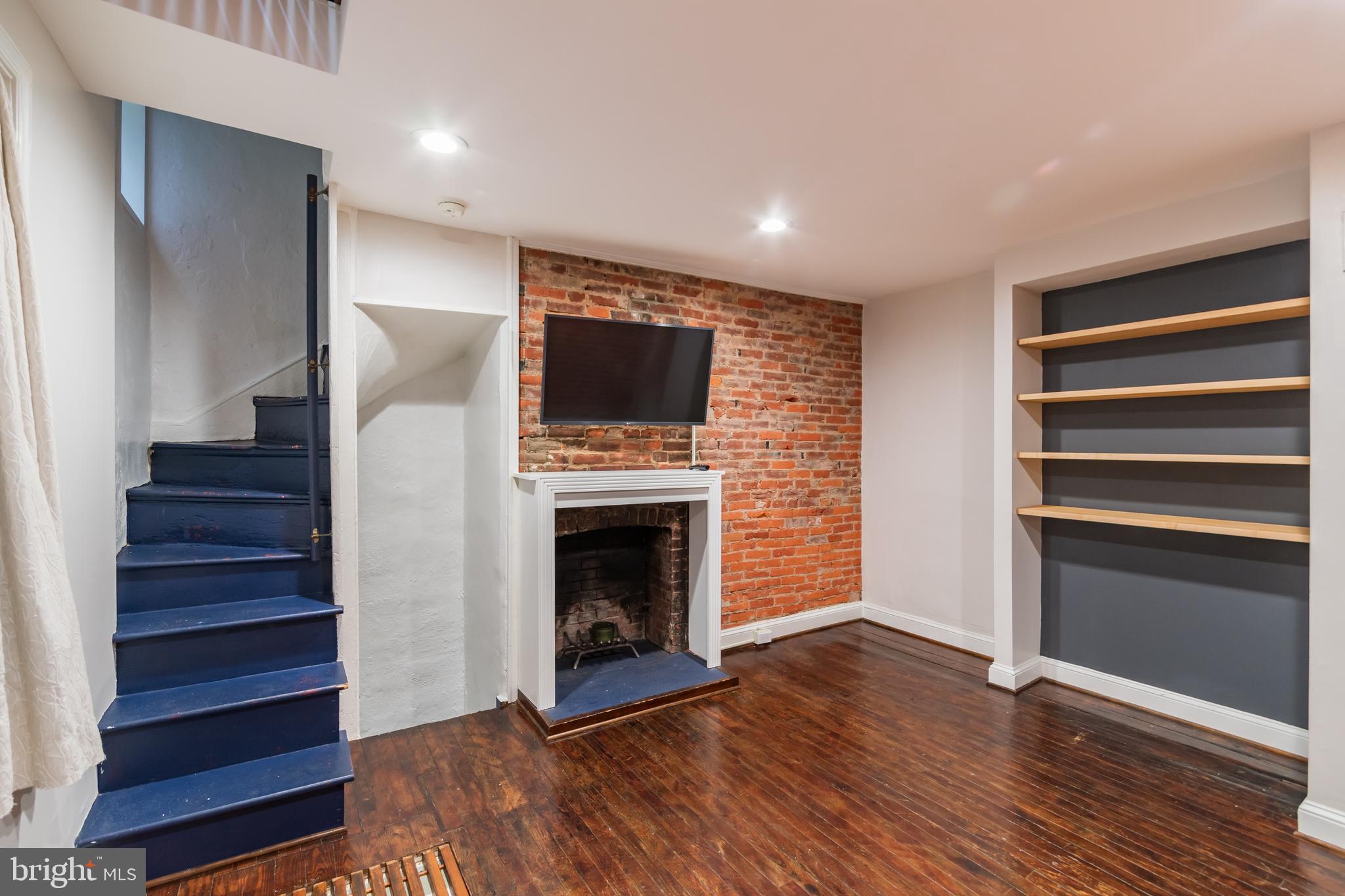 a view of a livingroom with wooden floor and a fireplace