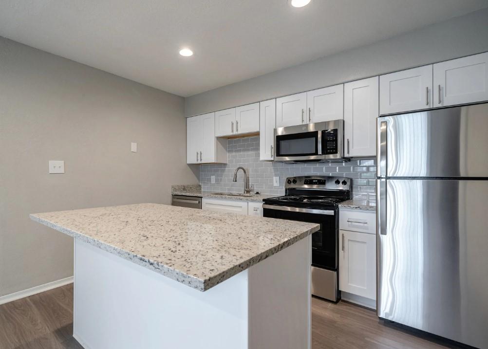 a kitchen with a refrigerator a microwave a sink and a stove top oven