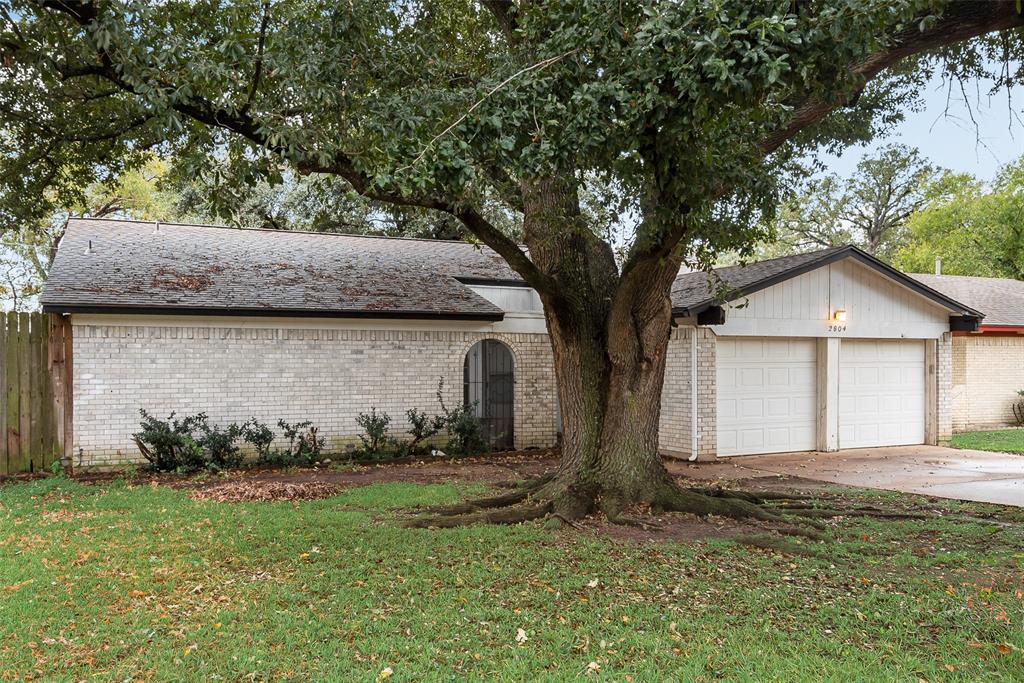 a view of a house with a yard and large tree