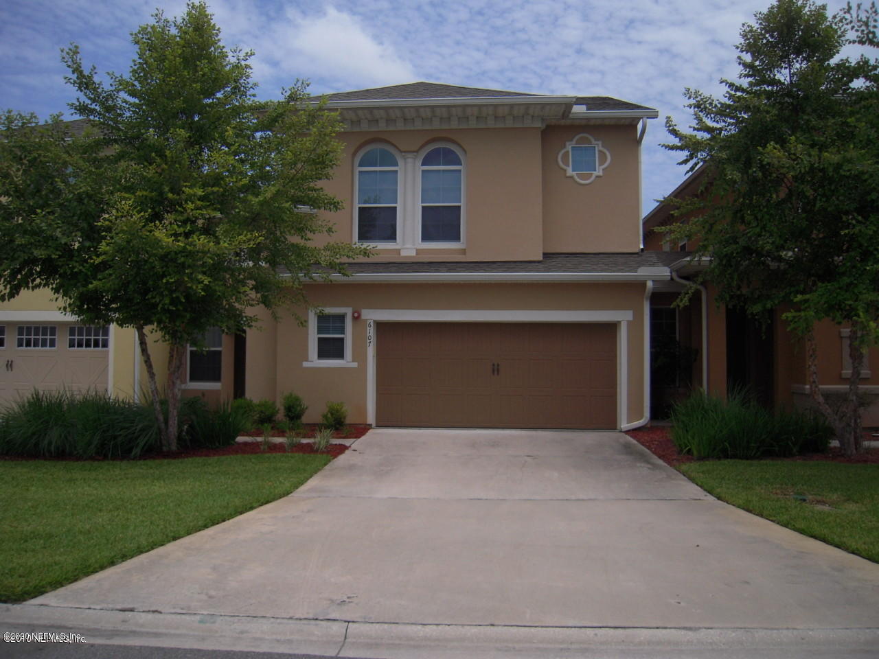 a front view of a house with a garden and trees