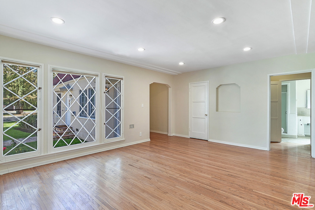 a view of an empty room with wooden floor and window