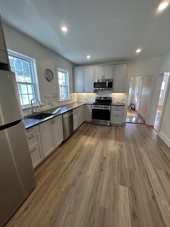 a kitchen with stainless steel appliances granite countertop wooden floors a stove and white cabinets