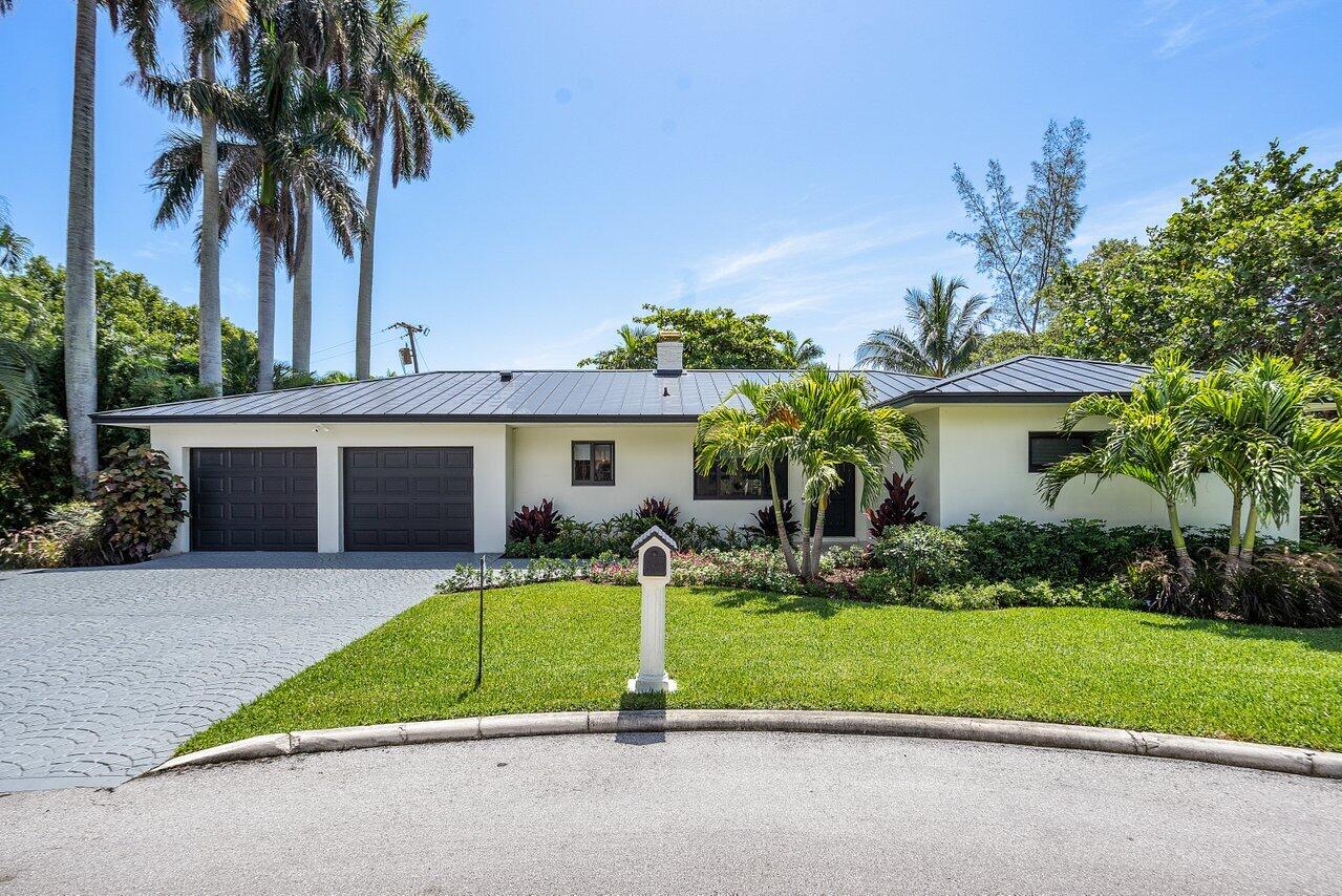 front view of house with a yard and palm trees