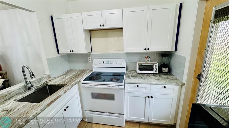 a kitchen with granite countertop a sink a stove and cabinets