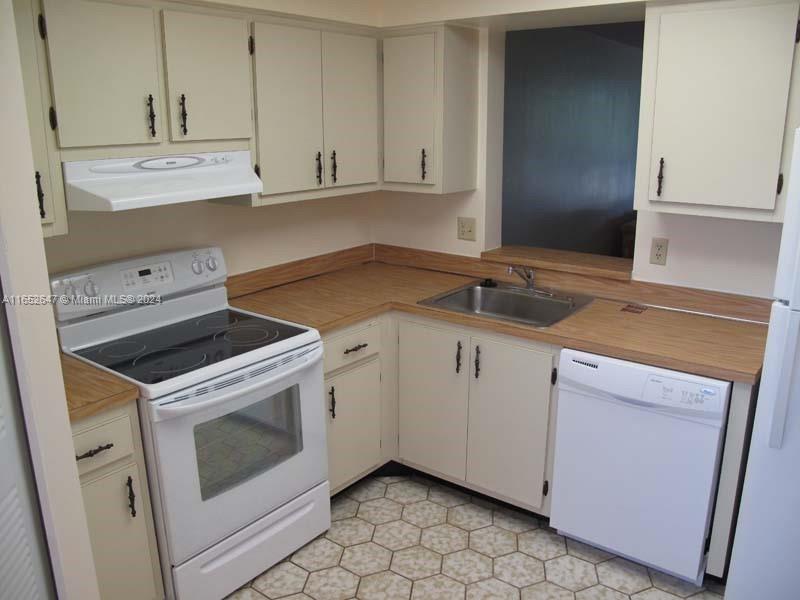 a kitchen with granite countertop white cabinets and white appliances