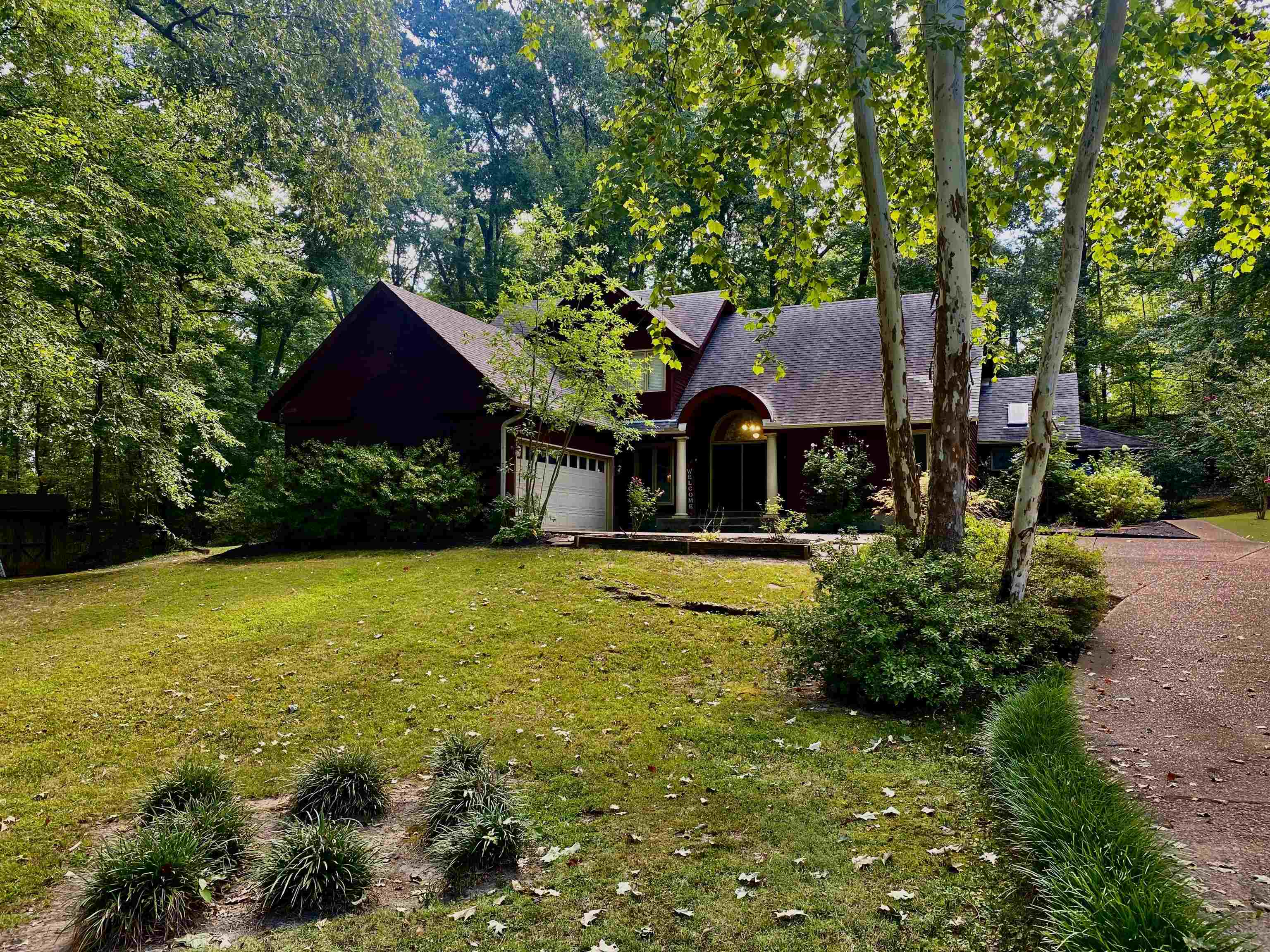 a view of house with garden space and trees in the background