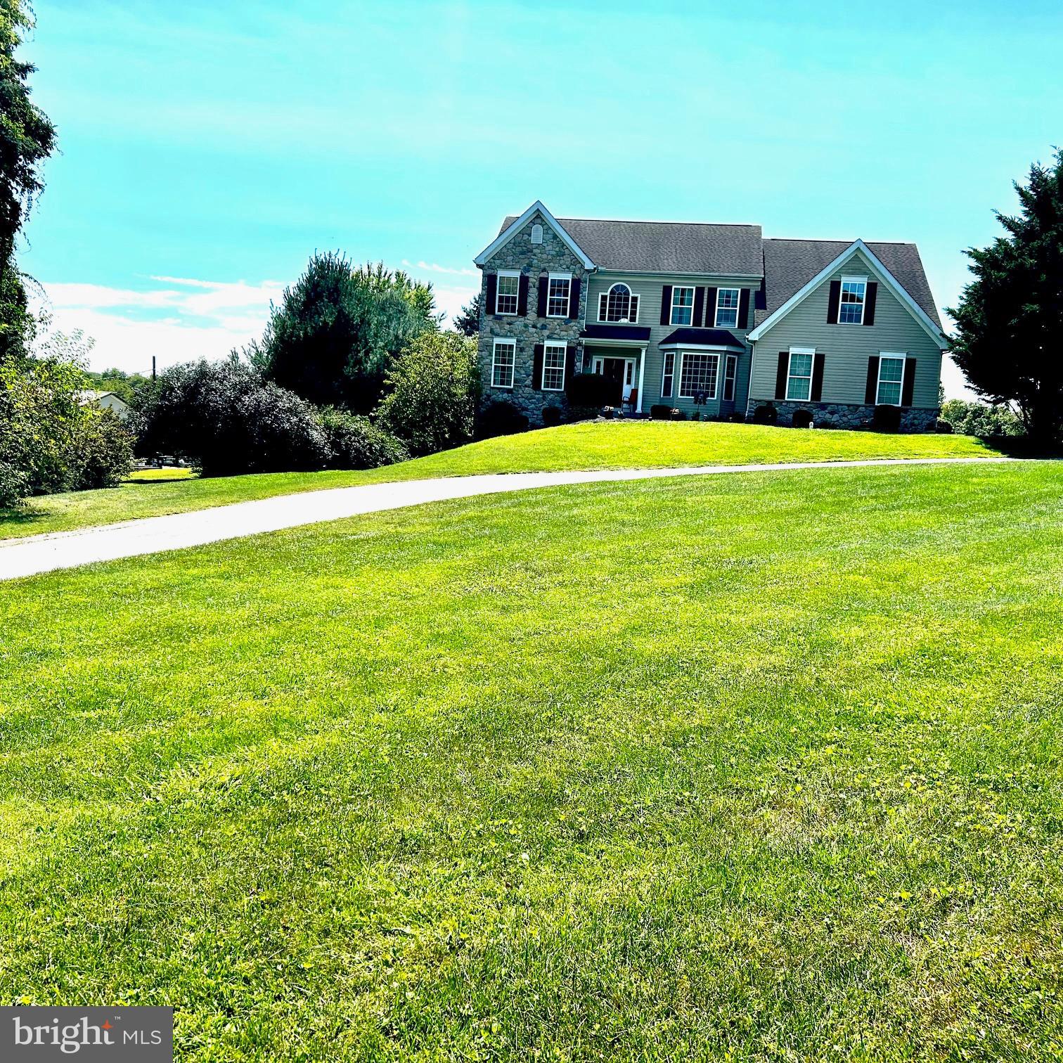 a view of a house with a big yard and large trees