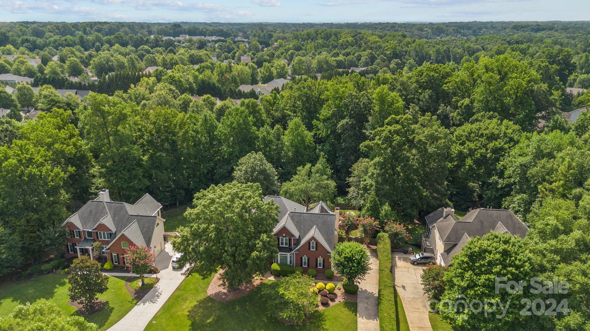 an aerial view of residential house with outdoor space and trees all around