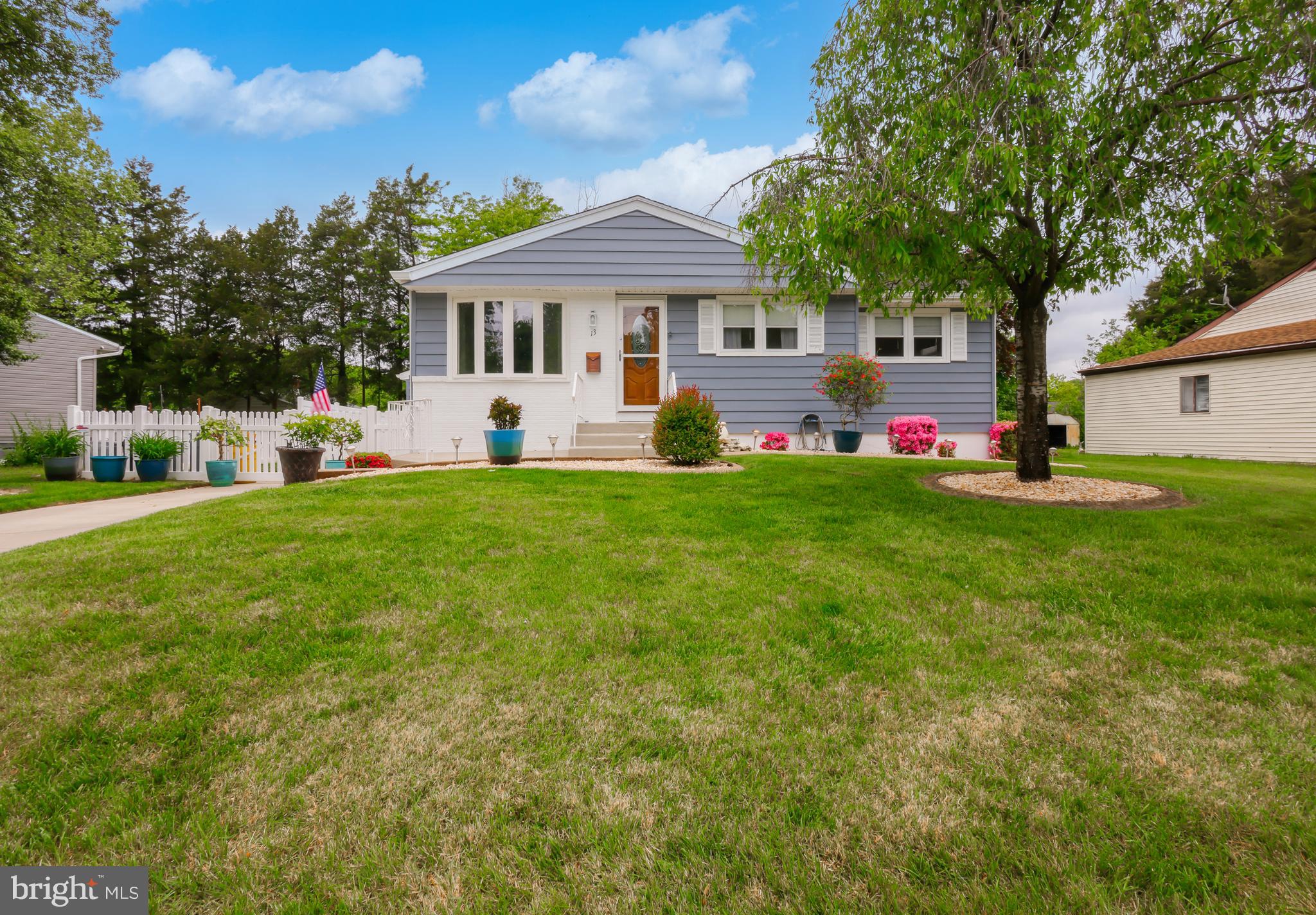 a front view of a house with a garden and trees