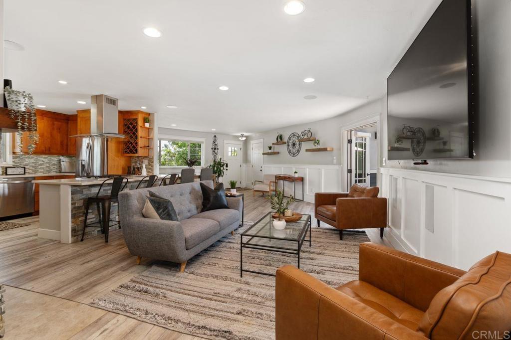 a living room with furniture kitchen view and a flat screen tv